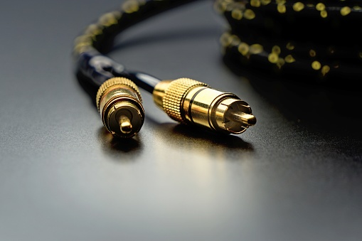 Black cinch audio cable with golden plugs macro on black