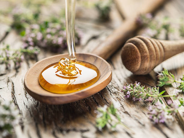 Herbal honey pouring into the wooden spoon. stock photo