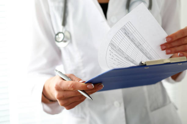 Female medicine doctor hand holding silver pen Female medicine doctor hand holding silver pen looking in clipboard pad closeup. Ward round, patient visit check, 911, medical calculation and statistics concept. Physician ready to examine patient Bureaucracy stock pictures, royalty-free photos & images