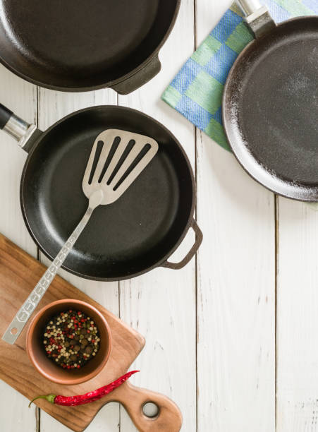 istock Several empty cast-iron frying pans on a white wooden background. 639848258
