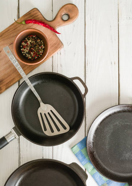 istock Several empty cast-iron frying pans on a white wooden background. 639848382