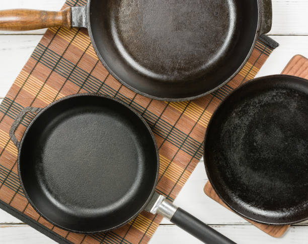 istock Several empty cast-iron frying pans on a white wooden background. 639849488