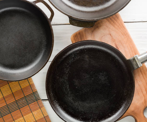 istock Several empty cast-iron frying pans on a white wooden background. 639849776