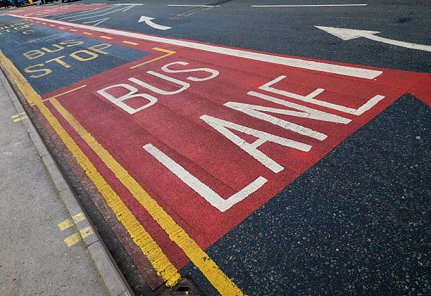 Bus Lane on City Street Carriageway in city with painted road markings indicating the left lane is for buses only. Other markings are for a bus stop, an indication that traffic should move to the right, no parking and no loading. A confusing scene in a small space! no parking sign photos stock pictures, royalty-free photos & images