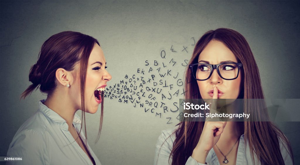 Angry woman screaming at herself with finger on lips gesture Split personality. Angry young woman screaming at herself with quiet finger on lips gesture. Negative human emotion face expression Friendship Stock Photo