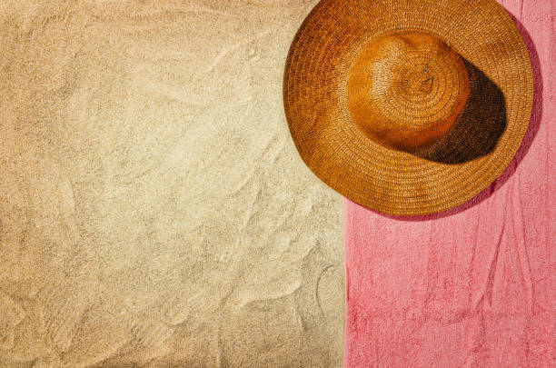 Top view of sandy beach with towel frame and summer accessories. Background with copy space and visible sand texture. Right border made of towel