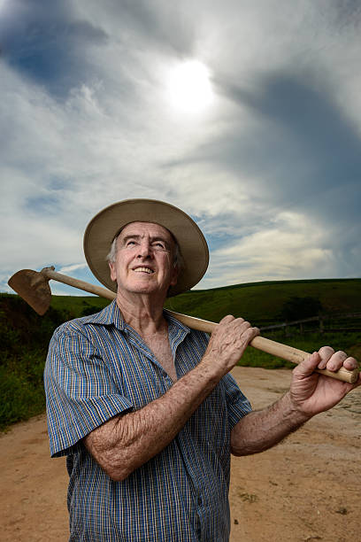 istock Hopeful rural worker holding a hoe looking the sky, Brazil 639869394