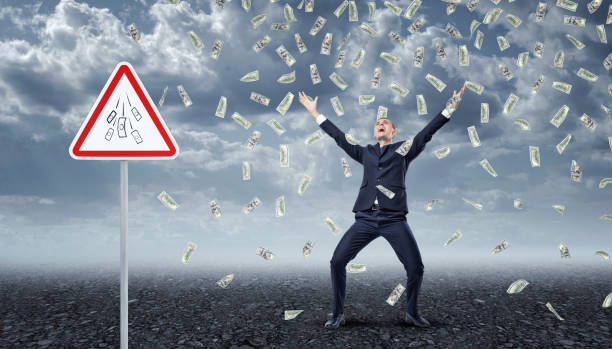 istock Ecstatic businessman standing under many dollar bills falling from the 639878978