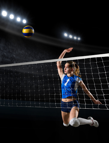 Female volleyball player performs a game moment on the indoor volleyball gym. She is wearing a sports cloth. Team sport and healthy lifestyle concept.