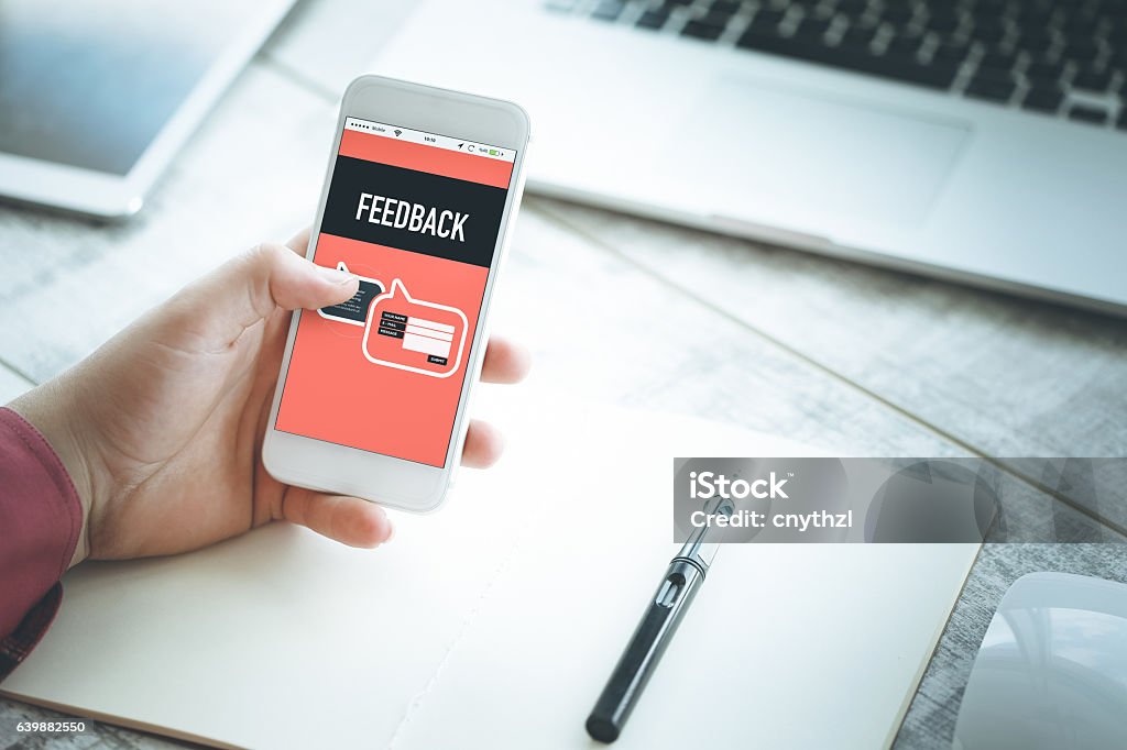 Smartphone in hand and showing Feedback concept on screen Rating Stock Photo