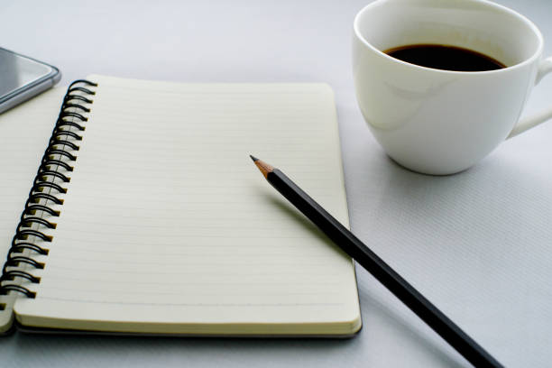 istock Coffee in white cup with Journal book and pencil 639883664