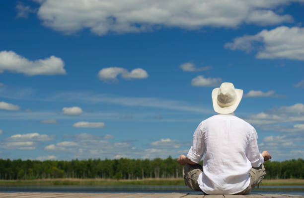 A man sits on a white folding chair on the lawn