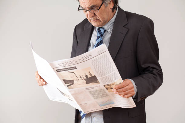 istock Businessman reading newspaper on gray background 639888048