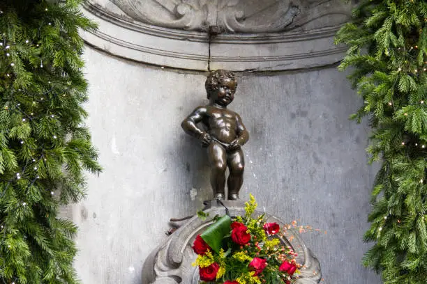 Manneken Pis Of Bruxelles with red flowers