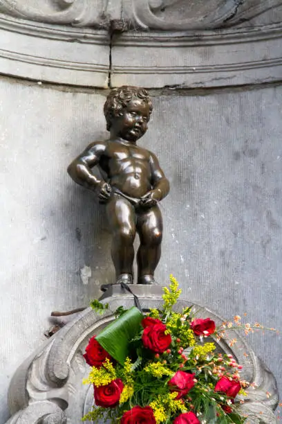 Manneken Pis Of Bruxelles with red flowers