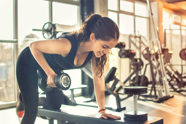 istock Young woman lifting weights on training class at gym. 639897508