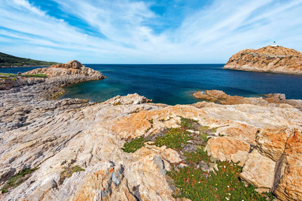 Red Porphyry rocks of Pietra Islet in Corsica Pietra Islet Coastline landscape in Ile-Rousse city in Corsica, with its lighthouse at right, Red Porphyry rocks texture is at foreground, Haute-Corse, France haute corse photos stock pictures, royalty-free photos & images