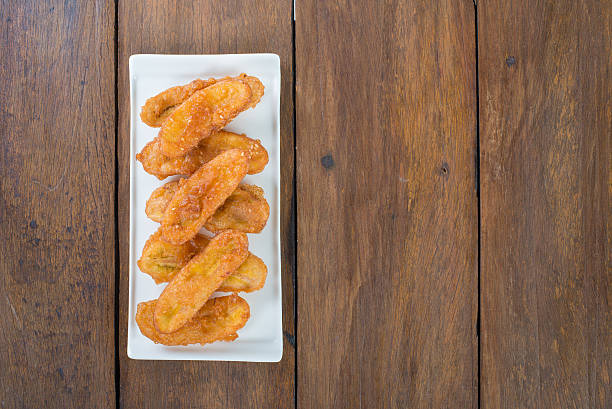 Salvadoran empanadas and yuca or cassava fritters deep frying in bubbling oil. Delicious and typical street food from El Salvador. Metal spoon scooping out four empanadas, ready for eating.