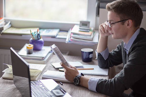 Male student learning for exam in his home office stock photo