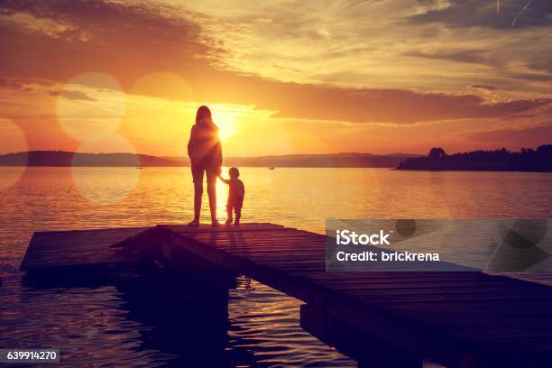 Silhouettes Of Mother And Her Son By The Lake Stock Photo - Download Image Now - Mother, Pier, Son