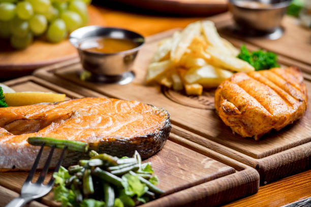 나무 판에 맛있고 아름다운 음식 - salmon cooked pepper plank 뉴스 사진 이미지