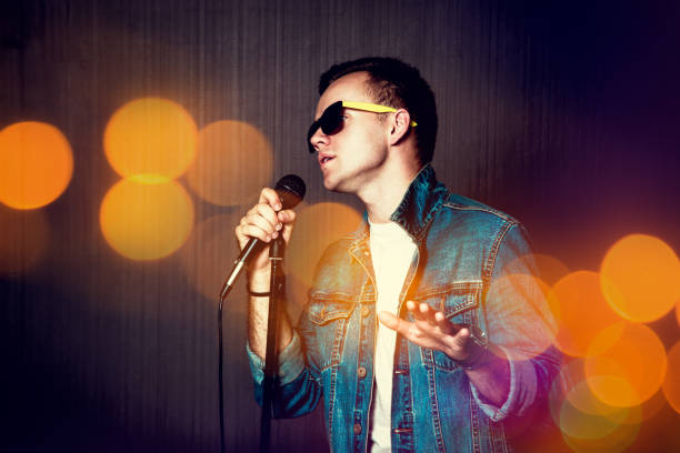 Guy Singing with Microphone. Bokeh Background. stock photo