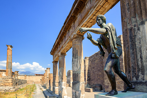 Ruins of the antique Temple of Apollo with bronze Apollo statue in Pompeii, Naples, Italy. Pompeii was destroyed by Vesuvius eruption in 79 AD.