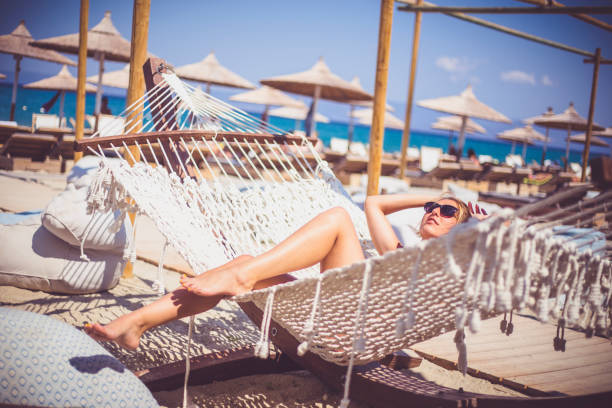 istock Happy young woman lying in hammock on tropical beach 639919756