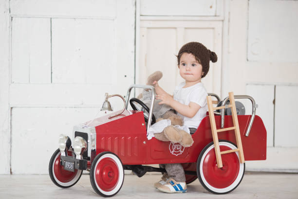 istock Child riding in red car. Kid smiling in a brown 639925588