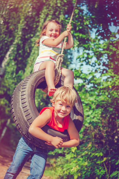 kids swinging in summer - freedom tire swing tire swing imagens e fotografias de stock