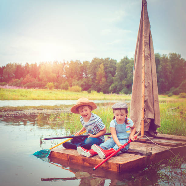 children traveling on raft - wood tranquil scene serene people lake imagens e fotografias de stock