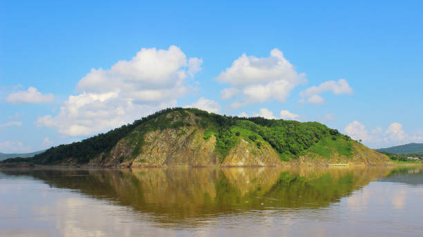 isola di roccia da sola in acqua ferma con riflesso pulito e - reflection water rock beach foto e immagini stock