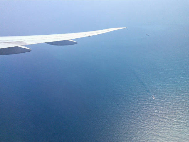 istock Aircraft wing above calm sea with still water and ships 639930846