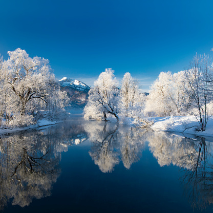 River Loisach flows into the Kochelsee, Alpen Glow at winter with rime and snow on the trees