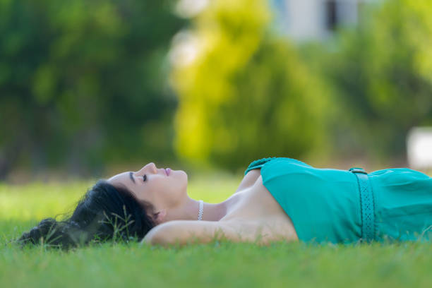istock Young woman lying on grass 639938296