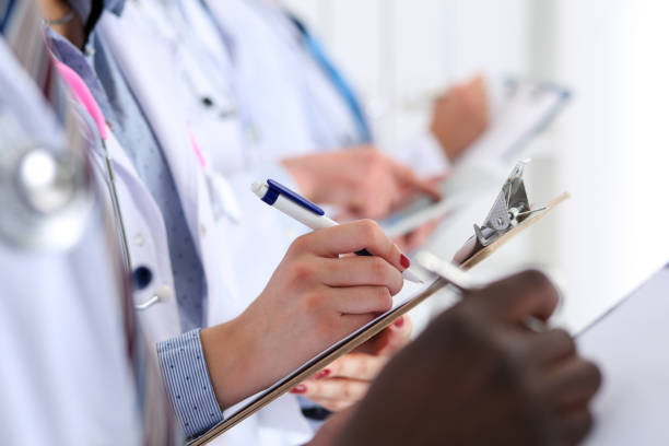 Group of doctors hold pens and clipboard pads