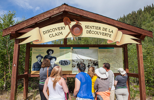 Dawson, Сanada - July 3, 2016: Tourists Reading about the Discovery Claim near Dawson in Canada's Yukon Territory - Editorial Image 