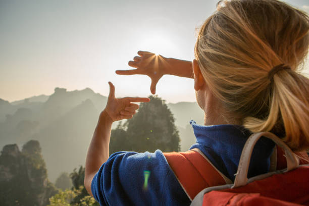 istock Young woman framing mountain landscape with hands 639944680