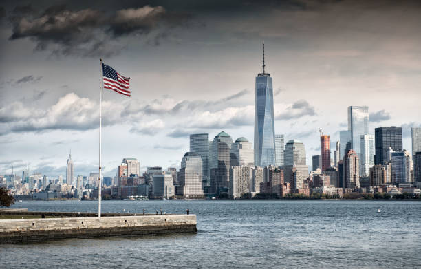American Flag in front of the Freedom Tower, New York Grey cloud above American Flag overlooking the Freedom Tower, New York City one world trade center photos stock pictures, royalty-free photos & images
