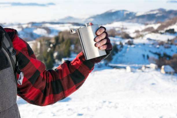 istock Male hand holding hip flask on a snowy mountain 639950234