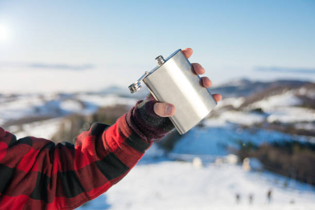 Male hand holding hip flask on a snowy mountain Male hand holding hip flask on a snowy mountain top hipflask stock pictures, royalty-free photos & images