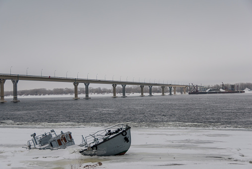 Sinking boat in a frozen river covered with ice