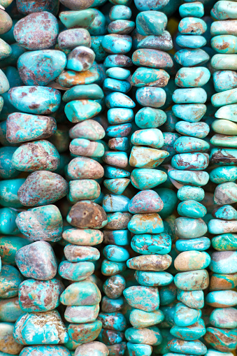 A close-up, full-frame of turquoise strands of beads and necklaces hanging.
