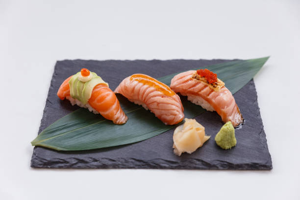 sushi au saumon brûlé et cru sur une assiette de pierre noire. - sushi styles photos et images de collection