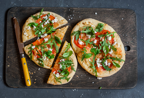 Naan pizza on a dark wooden background, top view