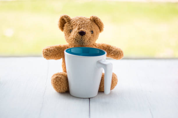 istock teddy bear with white coffee mug over garden background. 639962292