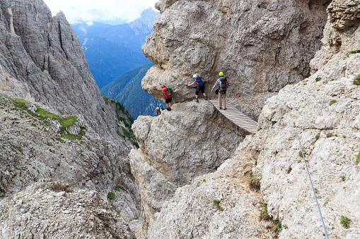 Auronzo, Italy - August 2, 2016: People climbing the Via Ferrata Severino Casara with bridge in Sexten Dolomites mountains, South Tyrol. The Dolomites are particularly renowned for their dramatic high mountain via ferratas.