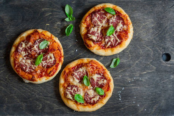 mini pizza salame su sfondo di legno scuro, vista dall'alto - antipasto appetizer basil bread foto e immagini stock