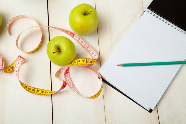 istock Green apples with measuring tape on a white wooden table 639963700