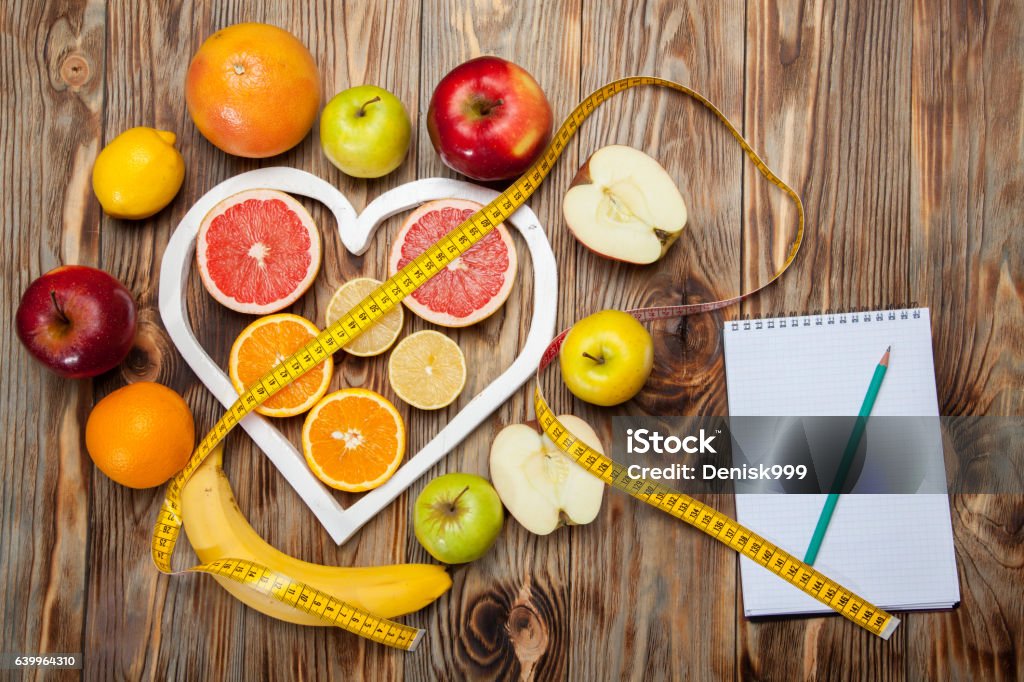 Fruit Diet, centimeter and plan on a wooden background Sheet of Diet Plan and fresh products on wooden table, top view Nutritionist Stock Photo